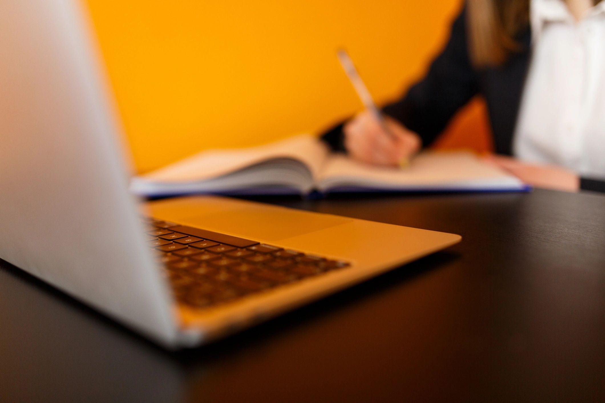 Person taking notes while learning on a laptop